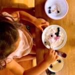 子どもがブルーベリーといちごが乗ったオーツを食べ始めています