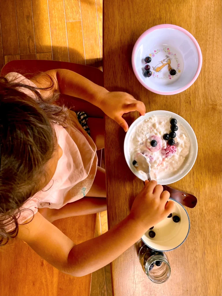 Child eating fermented oats with blueberries for breakfast