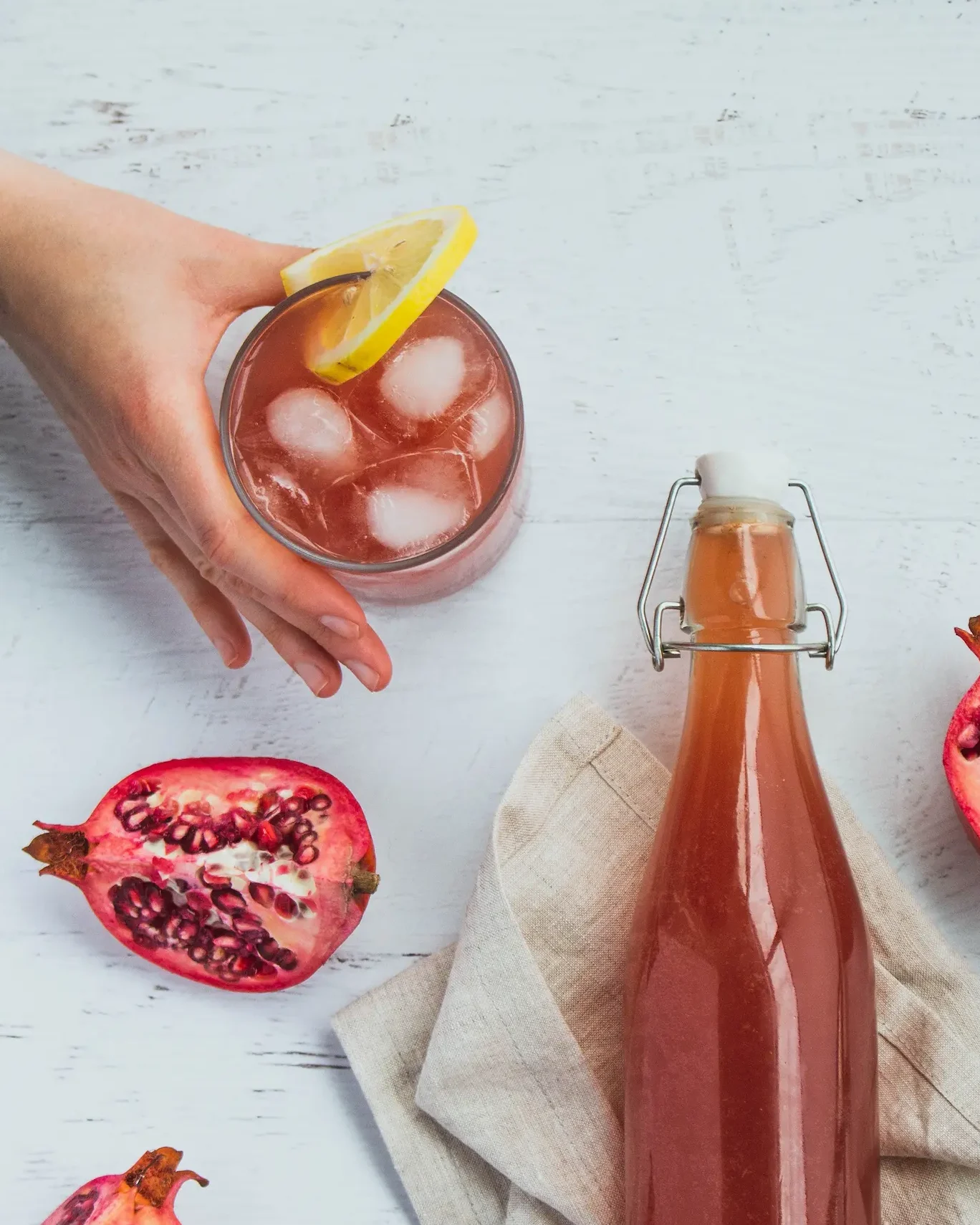 Passion fruit in a glass bin with fruits cut open next to it and a glass with ice cubes and juice in it.